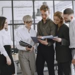 A diverse group of professionals collaborating and discussing documents in a modern office space.